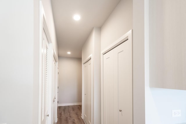 corridor with wood finished floors, recessed lighting, and baseboards