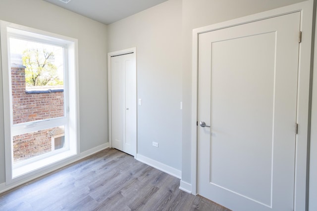 unfurnished bedroom with baseboards, wood finished floors, and a closet
