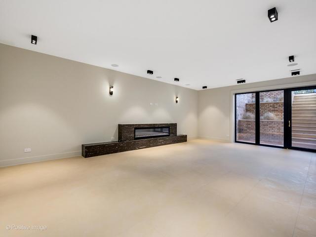 unfurnished living room featuring a glass covered fireplace and baseboards