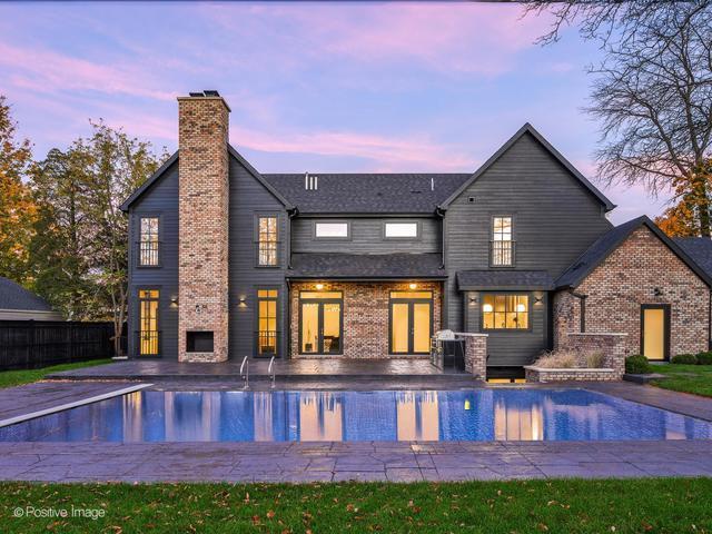 back of house with a chimney, a patio area, brick siding, and a fenced in pool