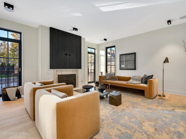 living room featuring a fireplace, baseboards, light wood-style floors, and a healthy amount of sunlight