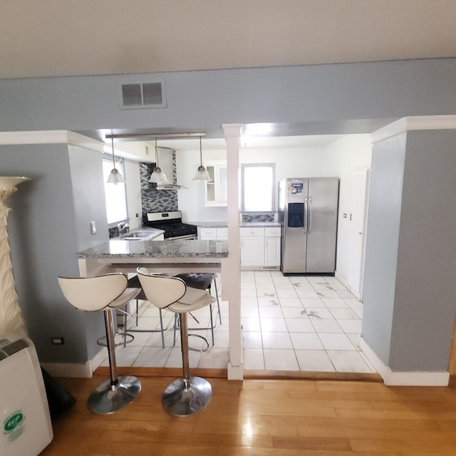 11258 S Normandy Ave, Worth, IL 60482 - kitchen with visible vents, appliances with stainless steel finishes, light wood-type flooring, a breakfast bar, and wall chimney exhaust hood