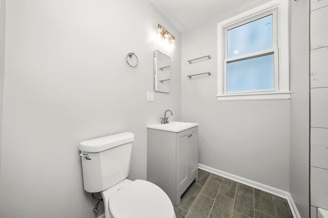 bathroom featuring vanity, baseboards, wood finish floors, and toilet