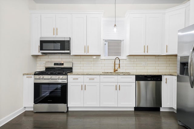 kitchen with decorative backsplash, baseboards, white cabinets, a sink, and appliances with stainless steel finishes