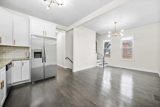kitchen with an inviting chandelier, white cabinetry, light stone counters, dark wood finished floors, and appliances with stainless steel finishes