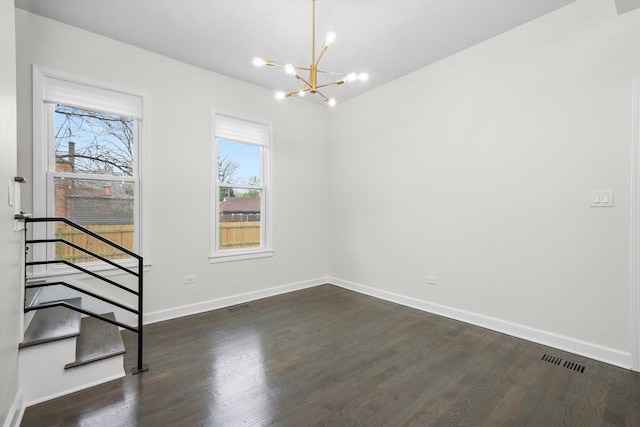 spare room featuring visible vents, dark wood-style flooring, baseboards, and a notable chandelier