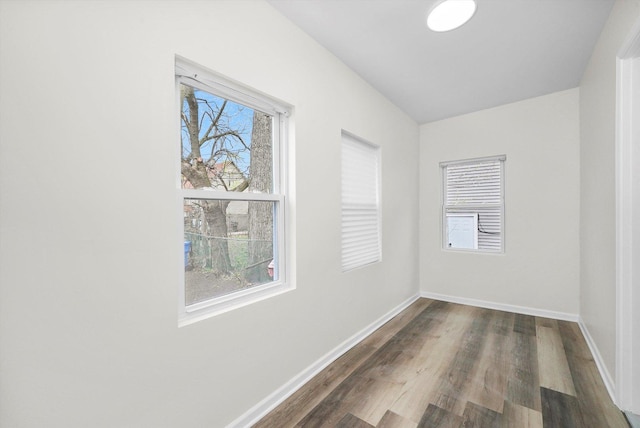 spare room with baseboards and dark wood-style floors