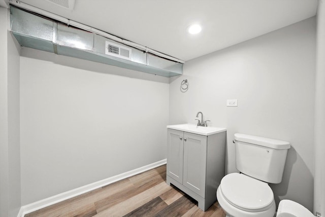 bathroom featuring visible vents, wood finished floors, vanity, baseboards, and toilet