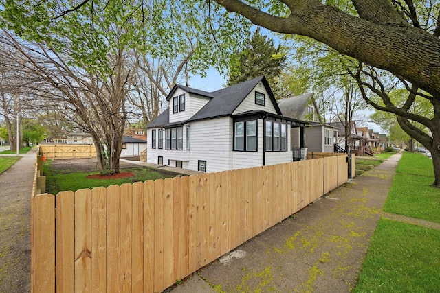 view of property exterior with a shingled roof, fence, and a residential view