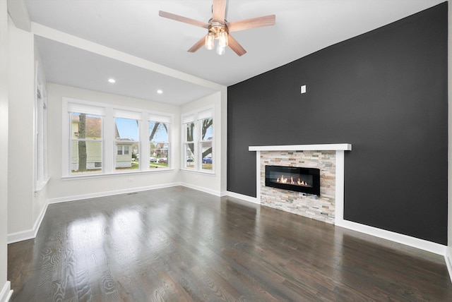 unfurnished living room featuring ceiling fan, a fireplace, recessed lighting, baseboards, and wood finished floors