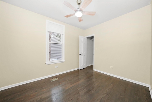 spare room featuring baseboards, a ceiling fan, dark wood-type flooring, and visible vents