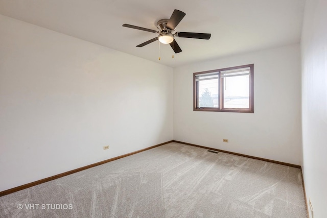 spare room with baseboards, a ceiling fan, light colored carpet, and visible vents
