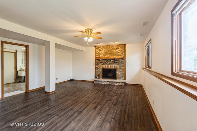 unfurnished living room with baseboards, a ceiling fan, a brick fireplace, and wood finished floors