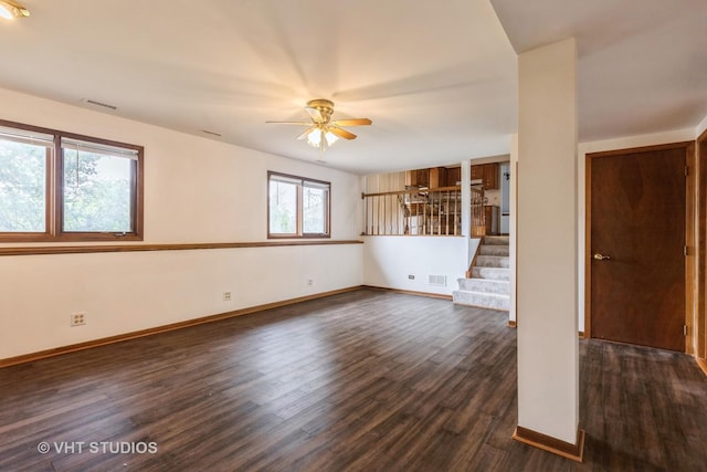 unfurnished room with visible vents, dark wood finished floors, ceiling fan, and stairway