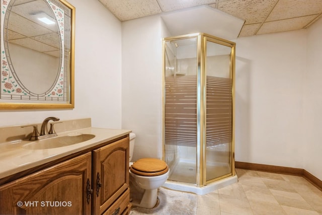 full bathroom featuring baseboards, vanity, a drop ceiling, and a shower stall