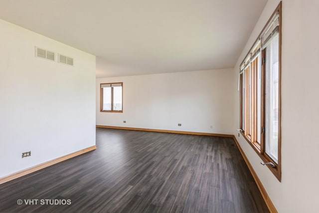 empty room with baseboards, dark wood-style floors, and visible vents
