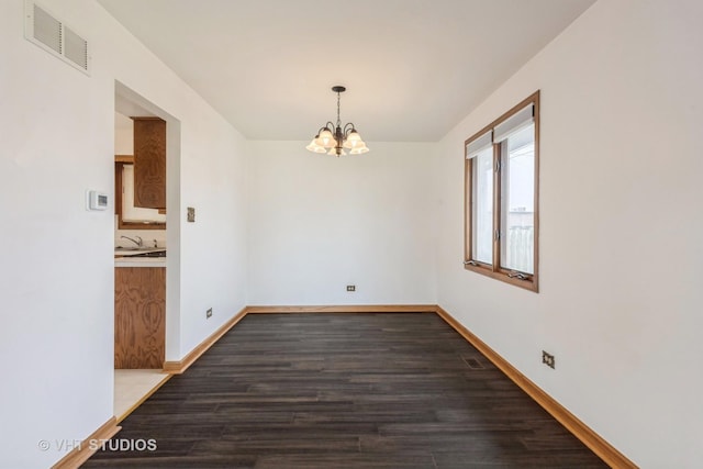 spare room with a notable chandelier, visible vents, baseboards, and dark wood-type flooring