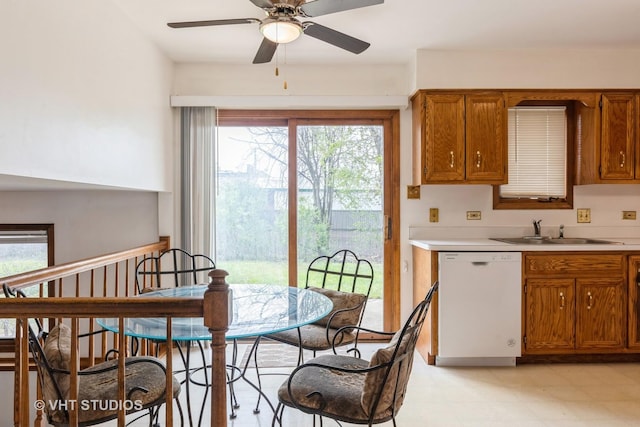 kitchen with brown cabinets, a sink, dishwasher, light countertops, and a ceiling fan