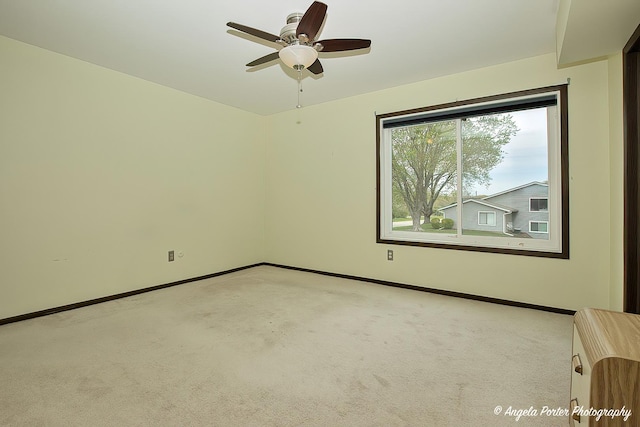 carpeted spare room with baseboards and a ceiling fan