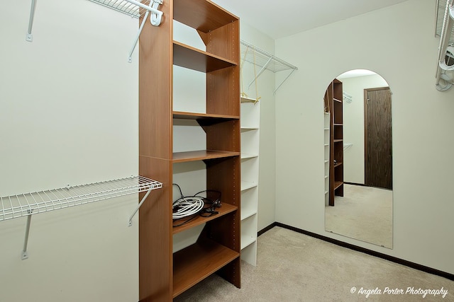 spacious closet featuring arched walkways and carpet