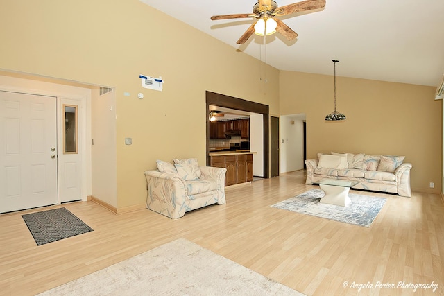 living area with visible vents, baseboards, high vaulted ceiling, a ceiling fan, and light wood-style flooring