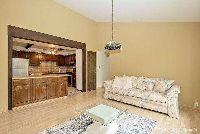 living area featuring baseboards, a ceiling fan, and light wood-style flooring