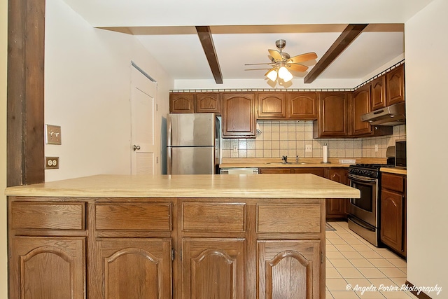 kitchen with a sink, a peninsula, under cabinet range hood, a ceiling fan, and appliances with stainless steel finishes