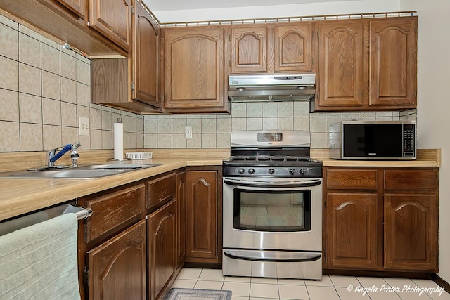 kitchen featuring a sink, light countertops, stainless steel appliances, and under cabinet range hood