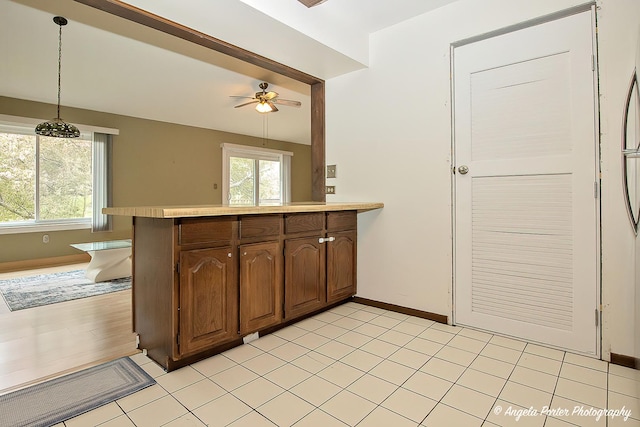 kitchen featuring ceiling fan, pendant lighting, light countertops, baseboards, and a peninsula