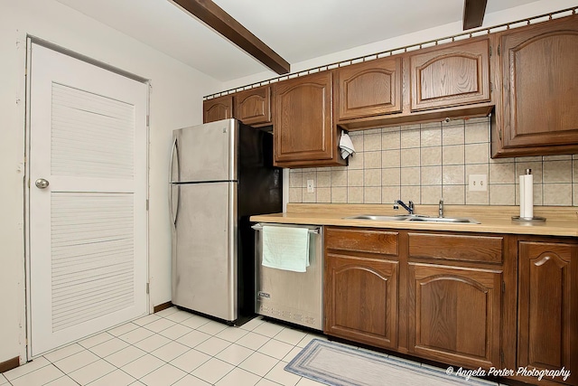 kitchen featuring backsplash, appliances with stainless steel finishes, beam ceiling, a sink, and light countertops