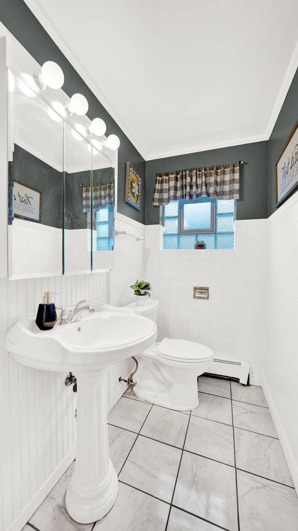 7022 W 64th St, Chicago, IL 60638 - bathroom with a wainscoted wall, a baseboard heating unit, toilet, tile walls, and marble finish floor