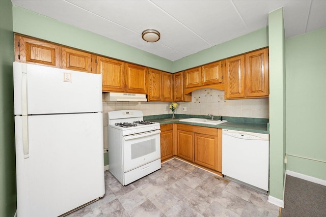 kitchen with a sink, white appliances, brown cabinetry, tasteful backsplash, and under cabinet range hood