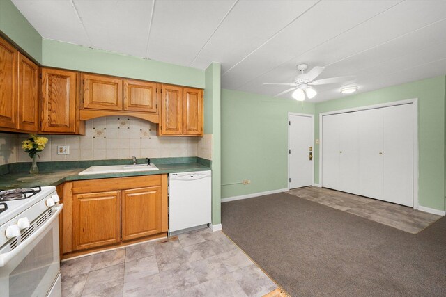 kitchen featuring ceiling fan, tasteful backsplash, a sink, baseboards, and white appliances