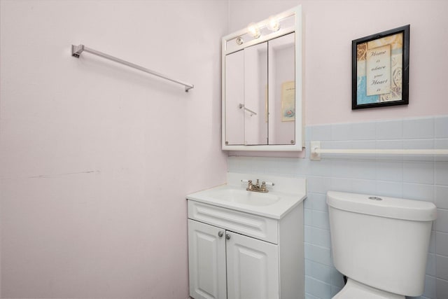 bathroom with vanity, toilet, and tile walls