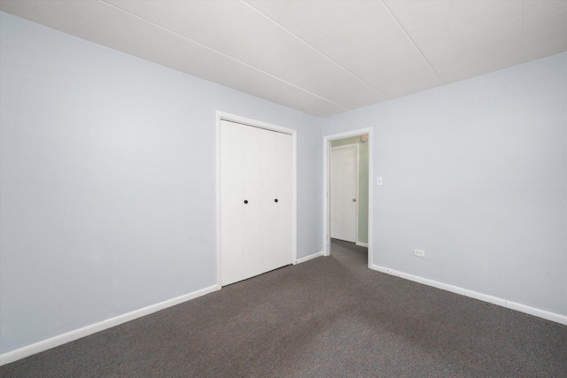spare room with dark colored carpet and baseboards
