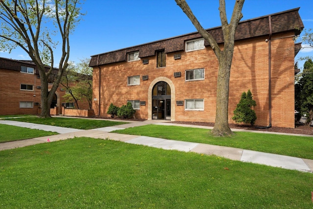 view of property featuring brick siding and a front lawn
