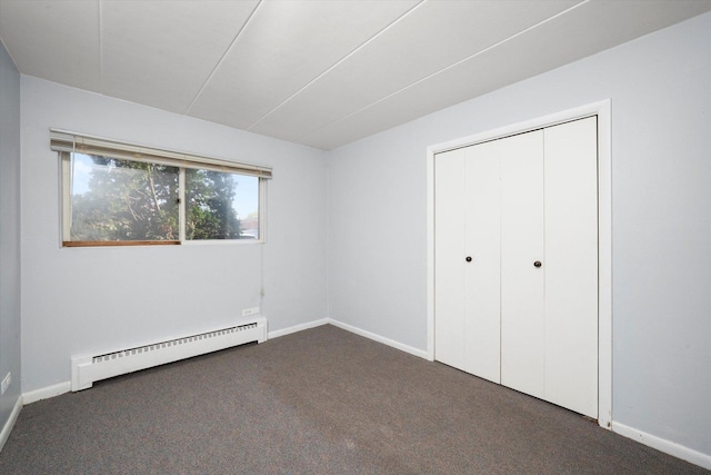 unfurnished bedroom with dark colored carpet, a baseboard radiator, baseboards, and a closet