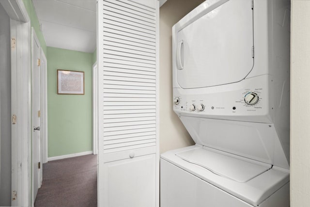 clothes washing area featuring carpet flooring, stacked washer / drying machine, baseboards, and laundry area