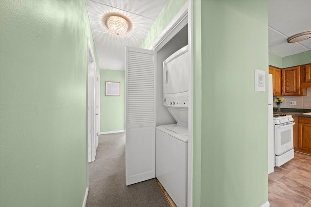washroom with stacked washer and dryer, laundry area, a chandelier, and baseboards