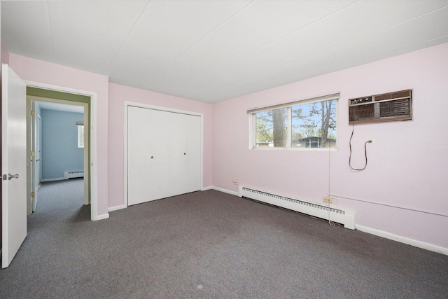 unfurnished bedroom with a baseboard heating unit, a wall unit AC, and dark colored carpet