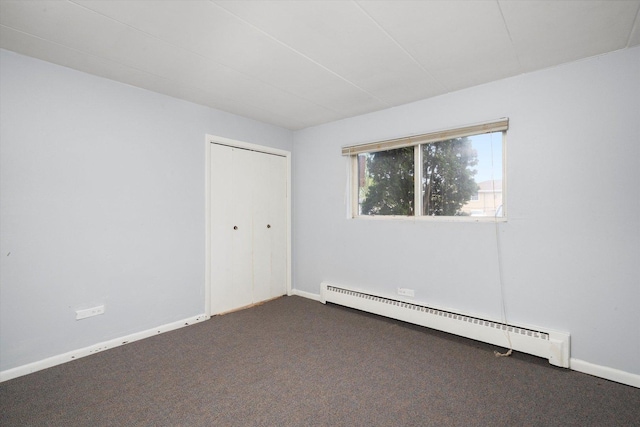 empty room with baseboards, a baseboard heating unit, and dark colored carpet
