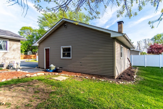 view of home's exterior with a yard, fence, and a chimney