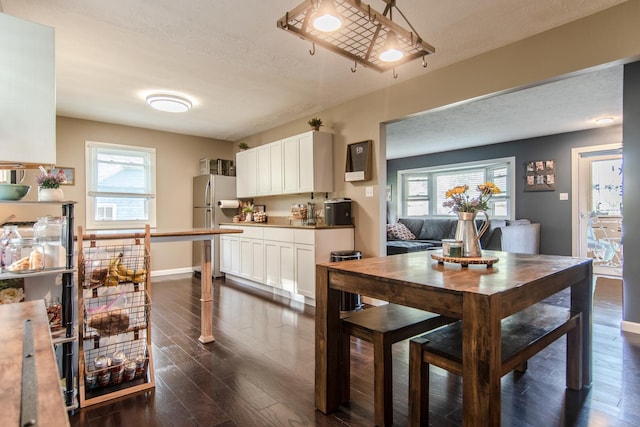 dining area featuring dark wood-style flooring, a textured ceiling, plenty of natural light, and baseboards