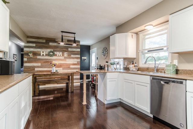 kitchen with wood walls, dishwasher, a sink, dark wood-style floors, and white cabinetry