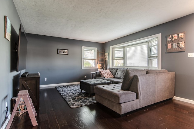 living area featuring baseboards, dark wood-style flooring, and a textured ceiling