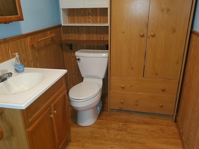bathroom with wood finished floors, vanity, a wainscoted wall, toilet, and wooden walls