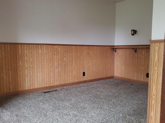empty room with carpet flooring, wood walls, and a wainscoted wall