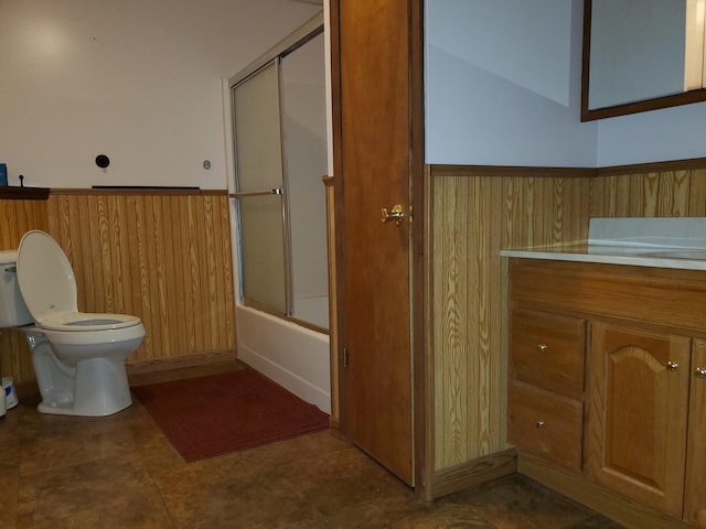 full bathroom featuring a wainscoted wall, vanity, toilet, wooden walls, and enclosed tub / shower combo