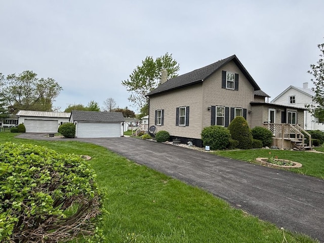 view of front of property featuring a detached garage, an outbuilding, a front yard, and a chimney