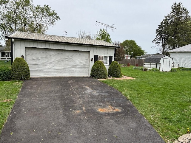 garage featuring fence, a storage unit, and driveway